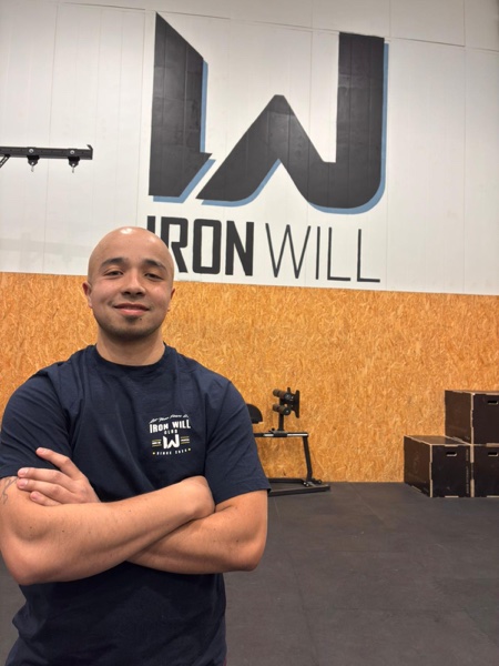 Andrés Castillo, coach de Iron Will Box, con el logo del box de fondo