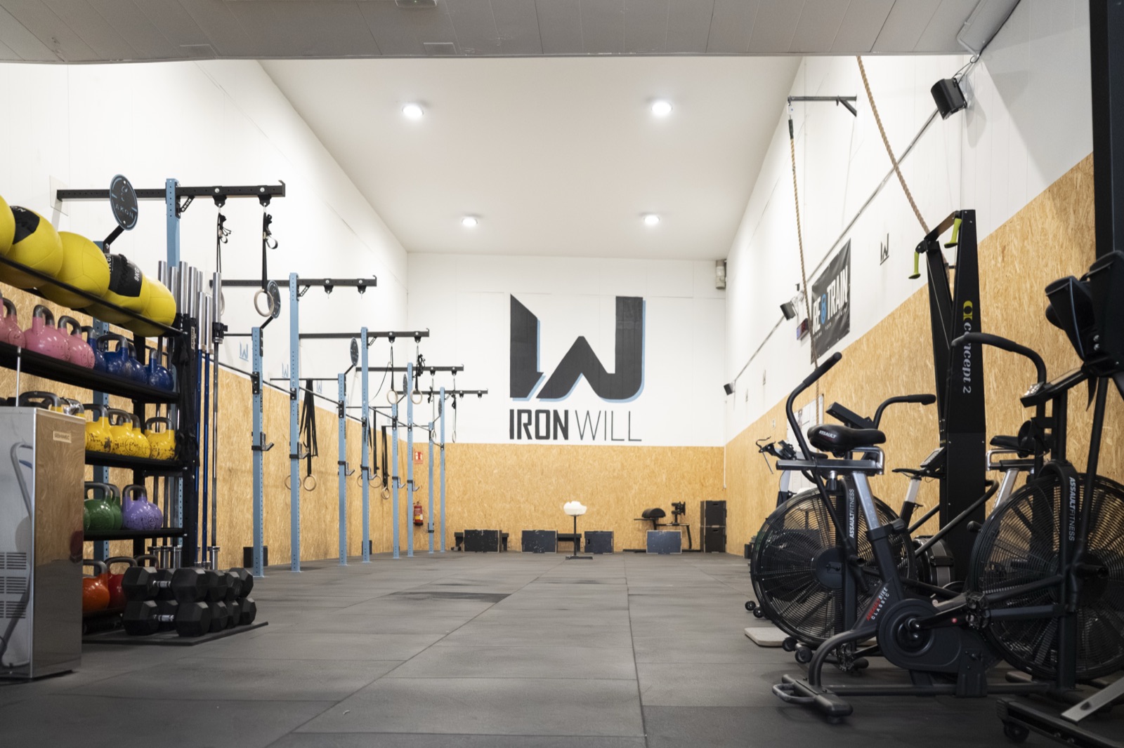 Interior del box Iron Will Box con racks, kettlebells y assault bikes