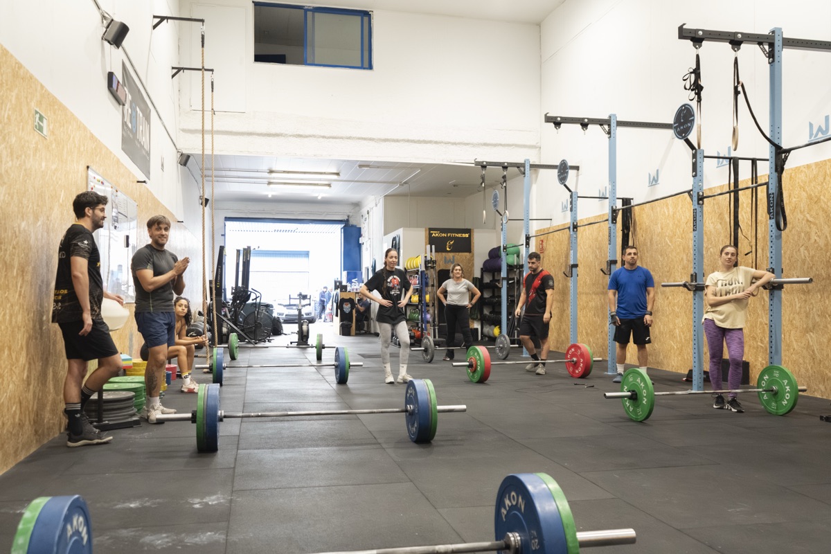 Socios preparándose con barras y discos antes de empezar la clase
