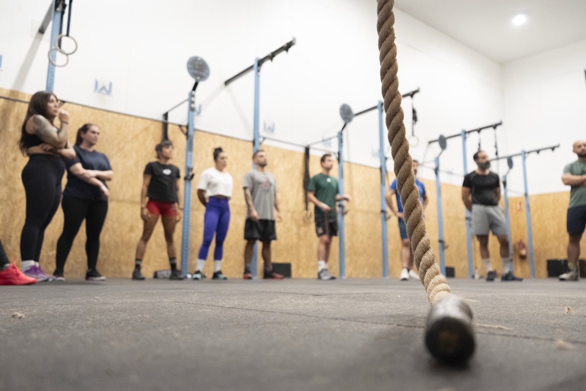 Plano cinematográfico de socios al fondo del box con cuerda en primer plano